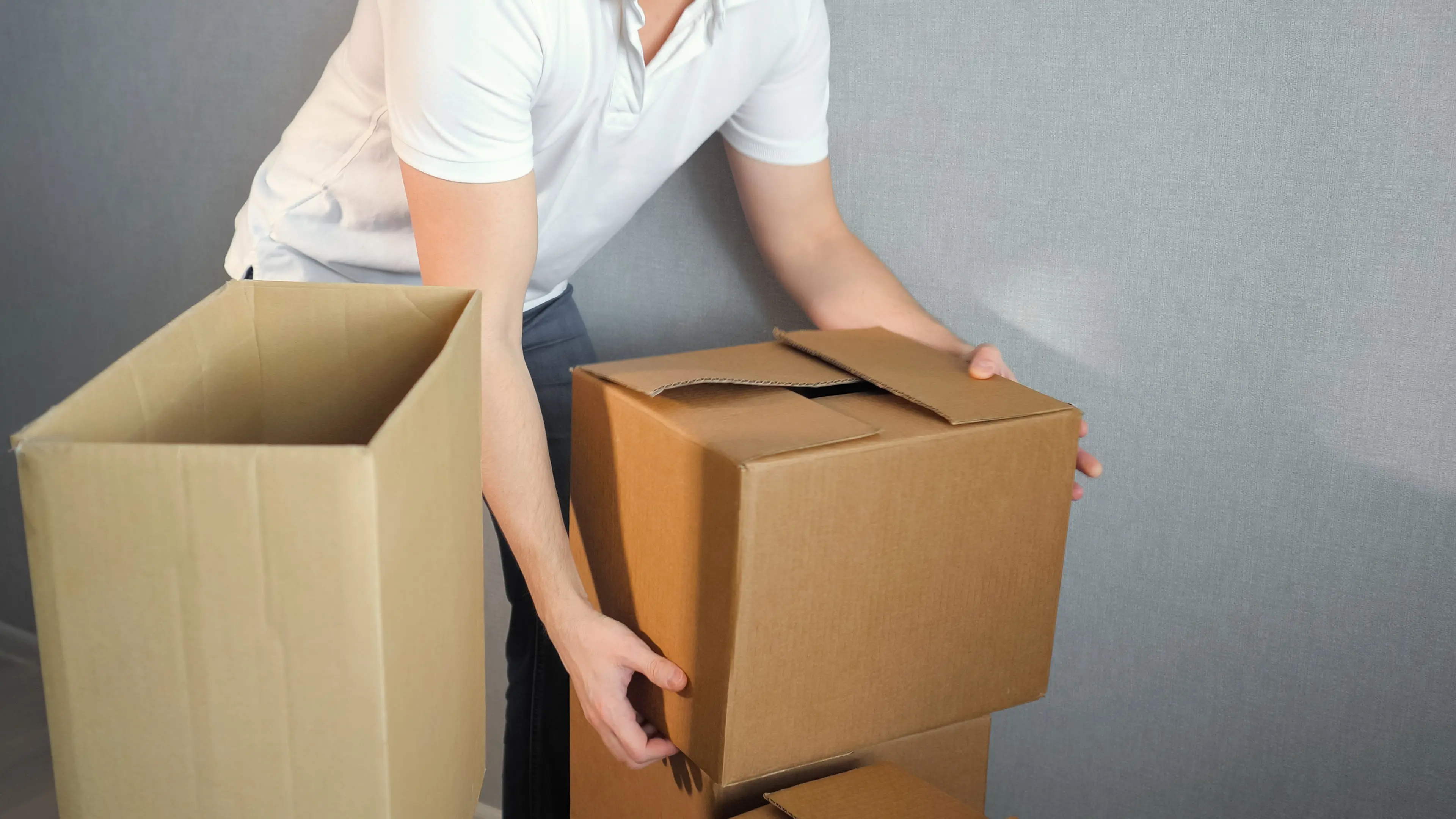 Young delivery service man carrying Boxes Into New Home On Moving Day, copy space