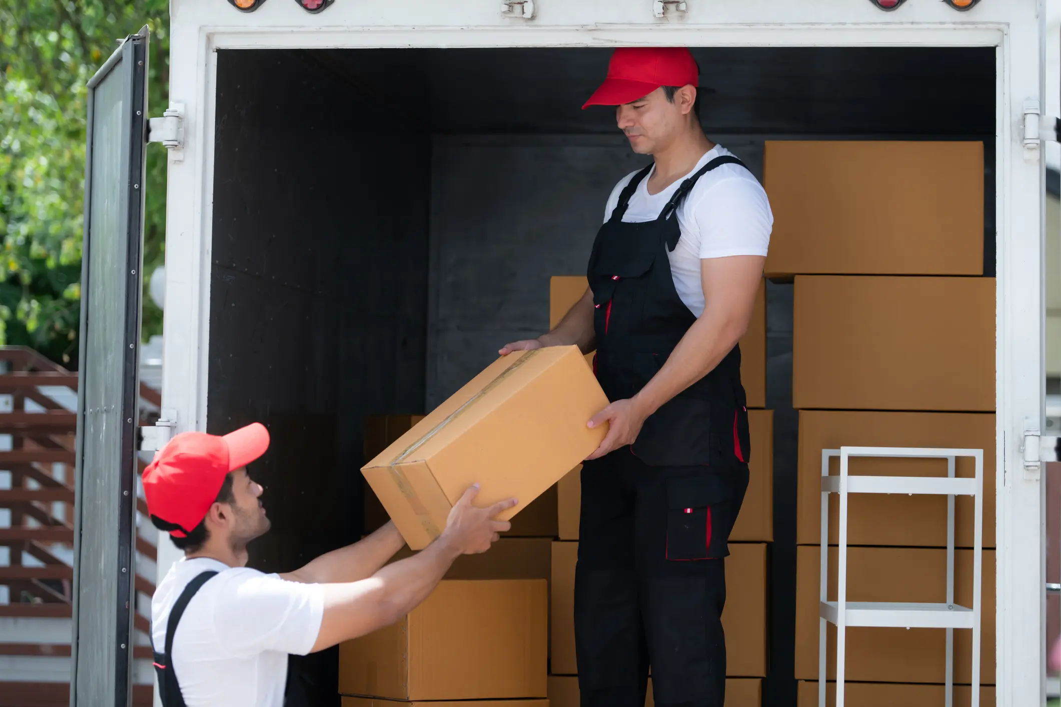 Asian delivery man in uniform delivering package to customer in back of truck.
