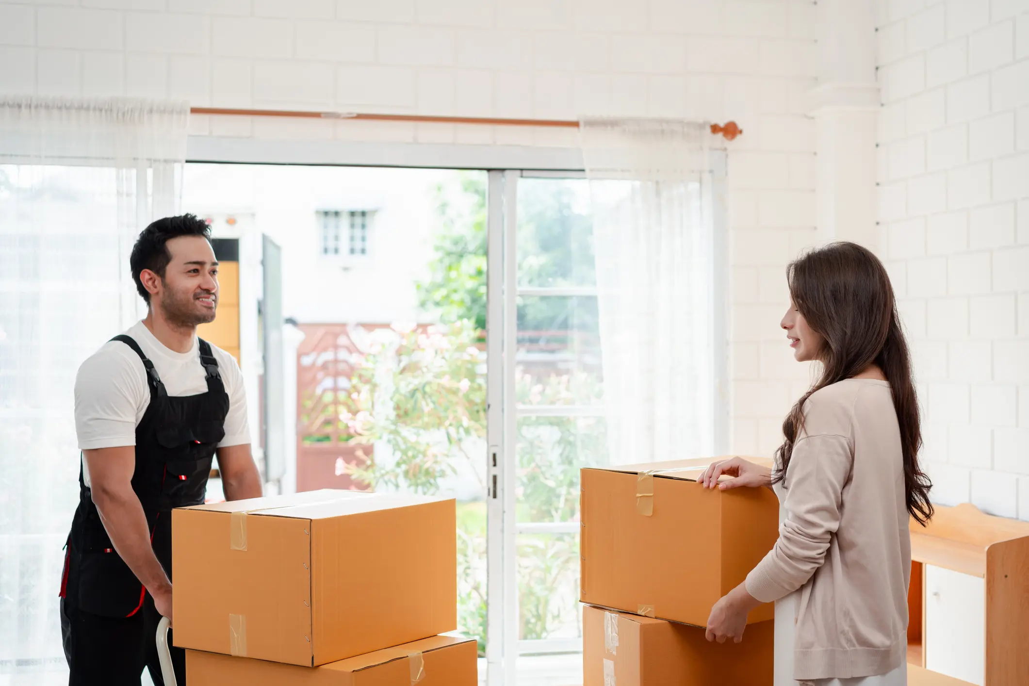 Woman check while unloading boxes and furniture from a pickup truck to a new house with service cargo two men movers worker in uniform lifting boxes. concept of Home moving and delivery.