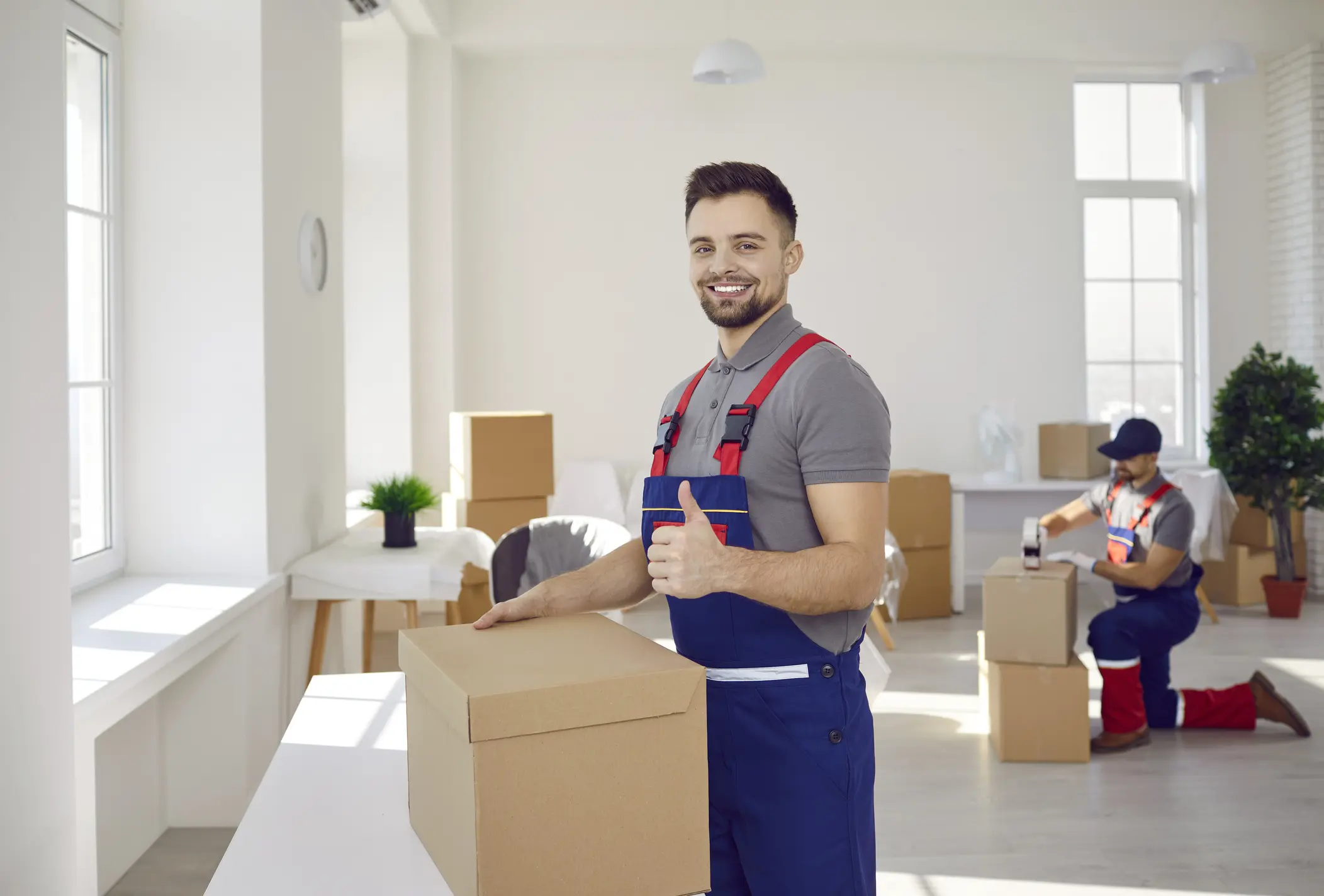 Happy male mover worker with cardboard box show thumbs up recommend good quality delivery company service. Smiling deliveryman with package give recommendation to moving or relocation help.